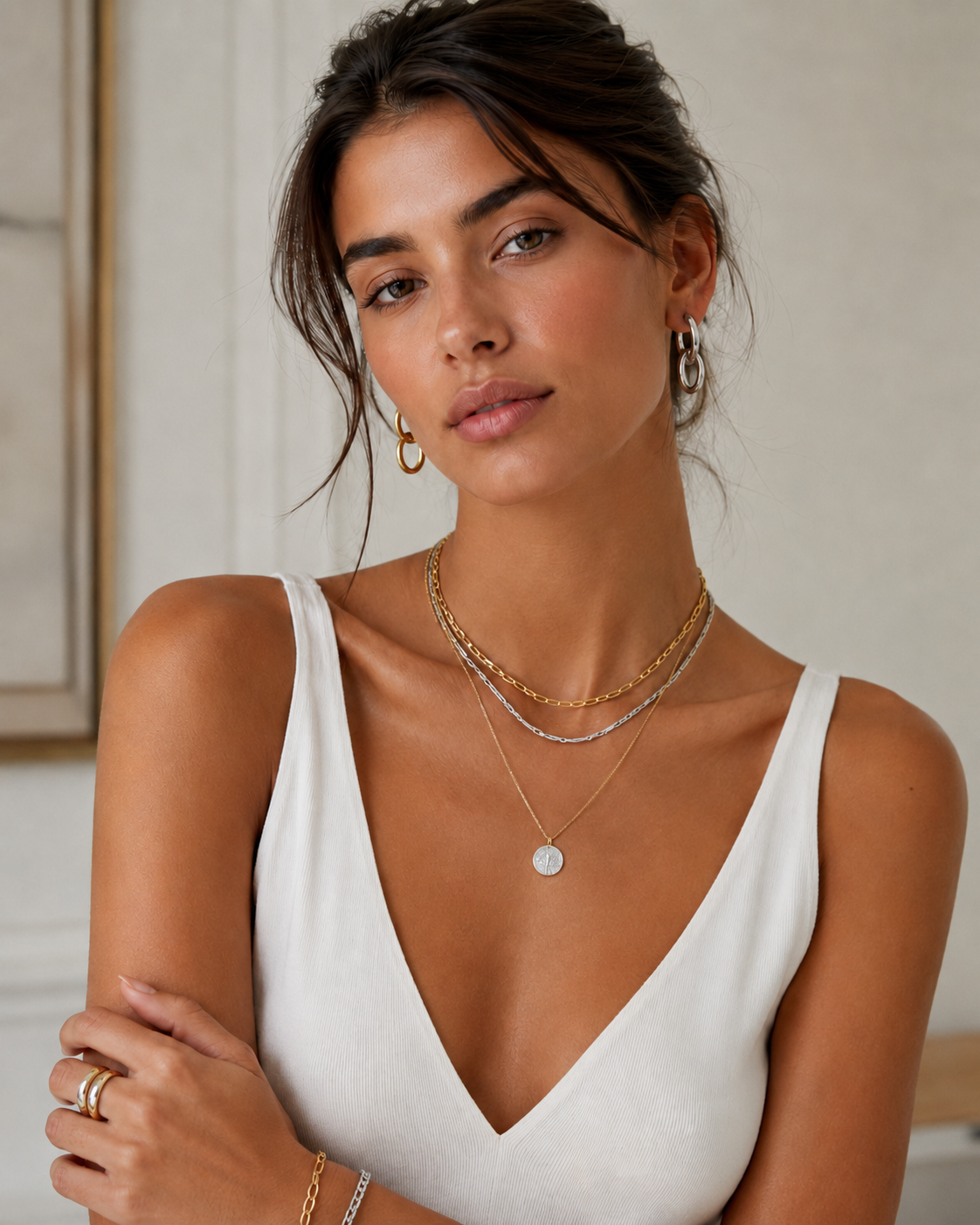 Woman wearing gold hoop earrings with layered gold and silver necklaces