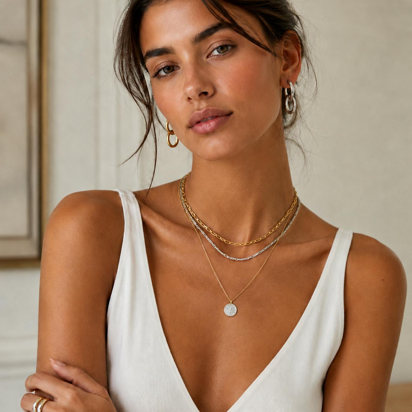 Can you mix gold and silver jewellery? Woman wearing gold hoop earrings with layered gold and silver necklaces