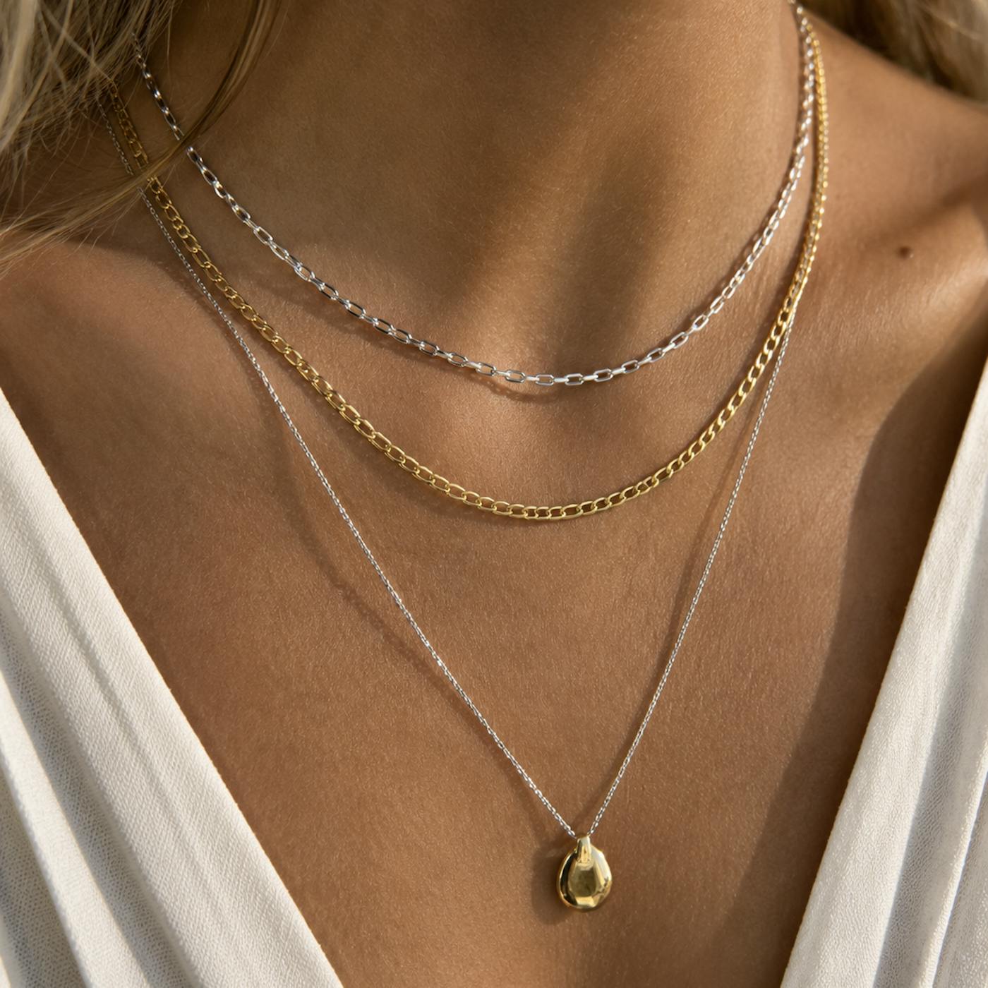 Can you mix gold and silver jewellery? Close-up of layered silver and gold necklaces with a gold pendant