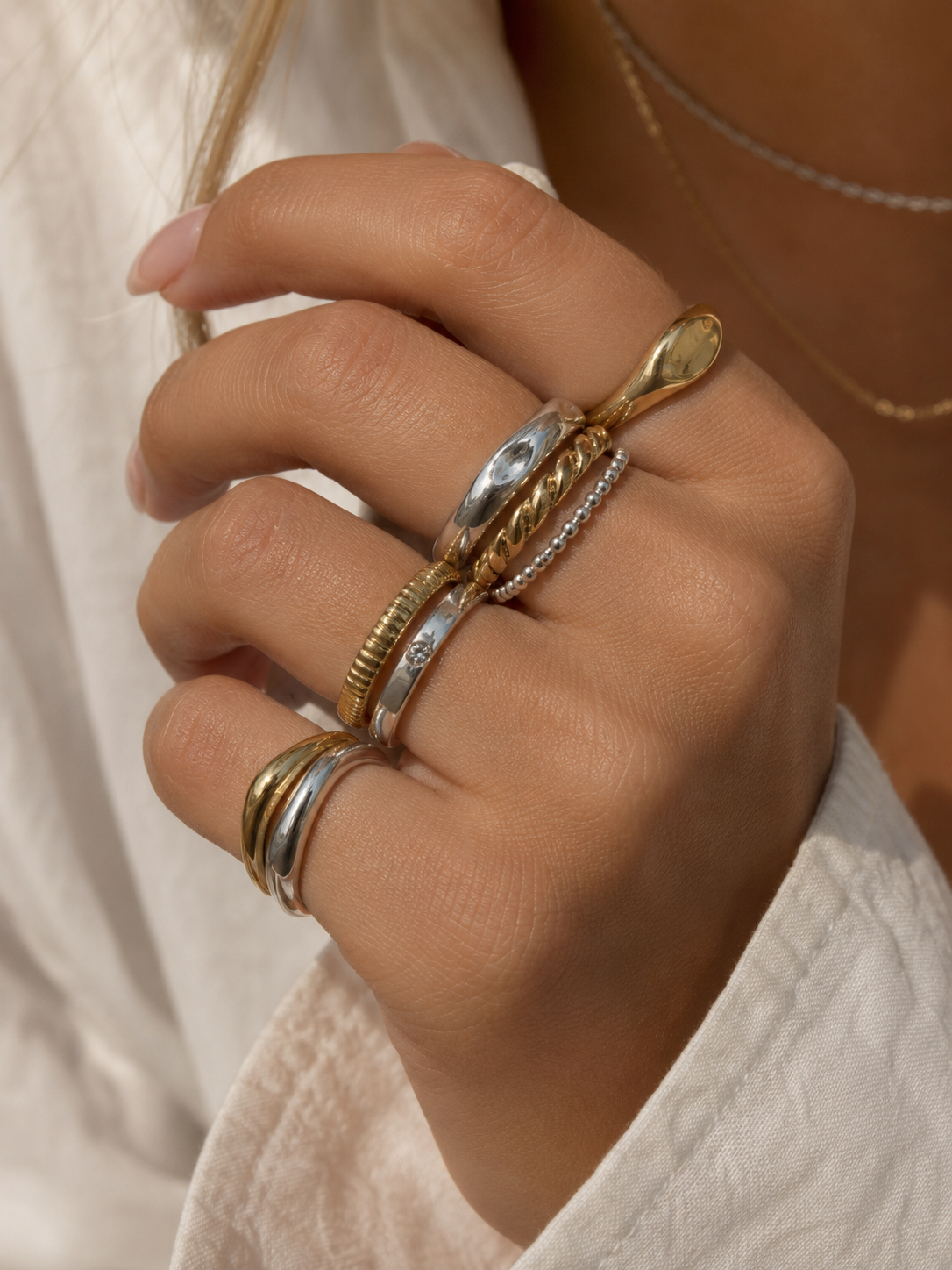 Hand wearing stacked gold and silver rings