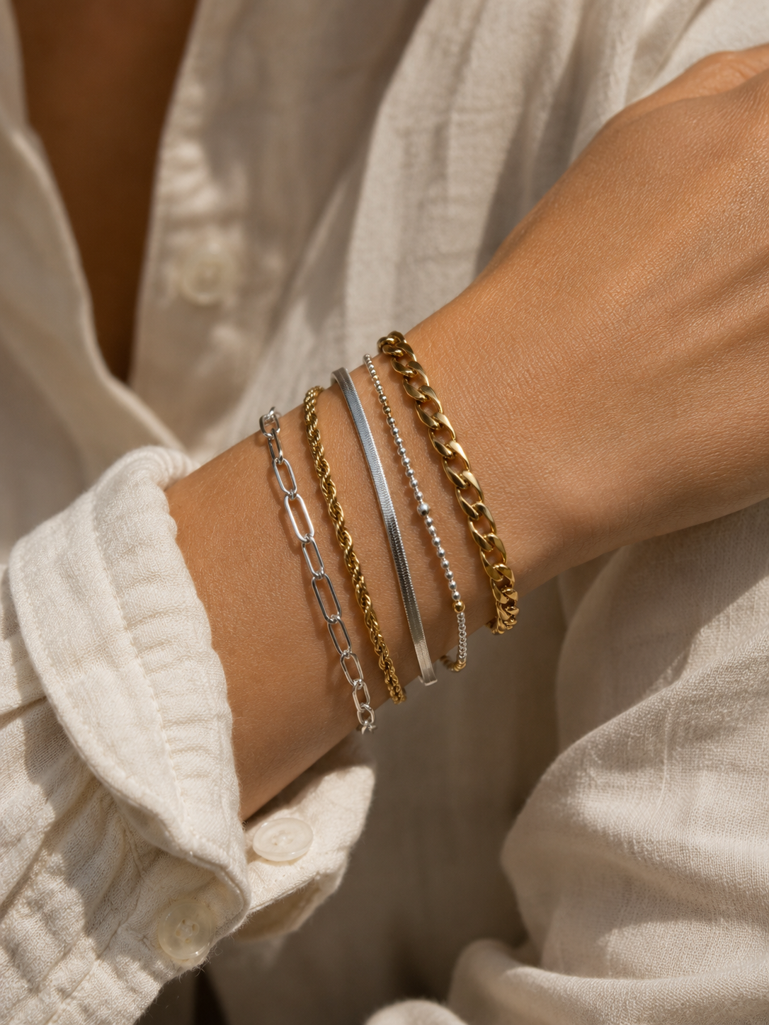 Wrist with stacked gold and silver chain bracelets