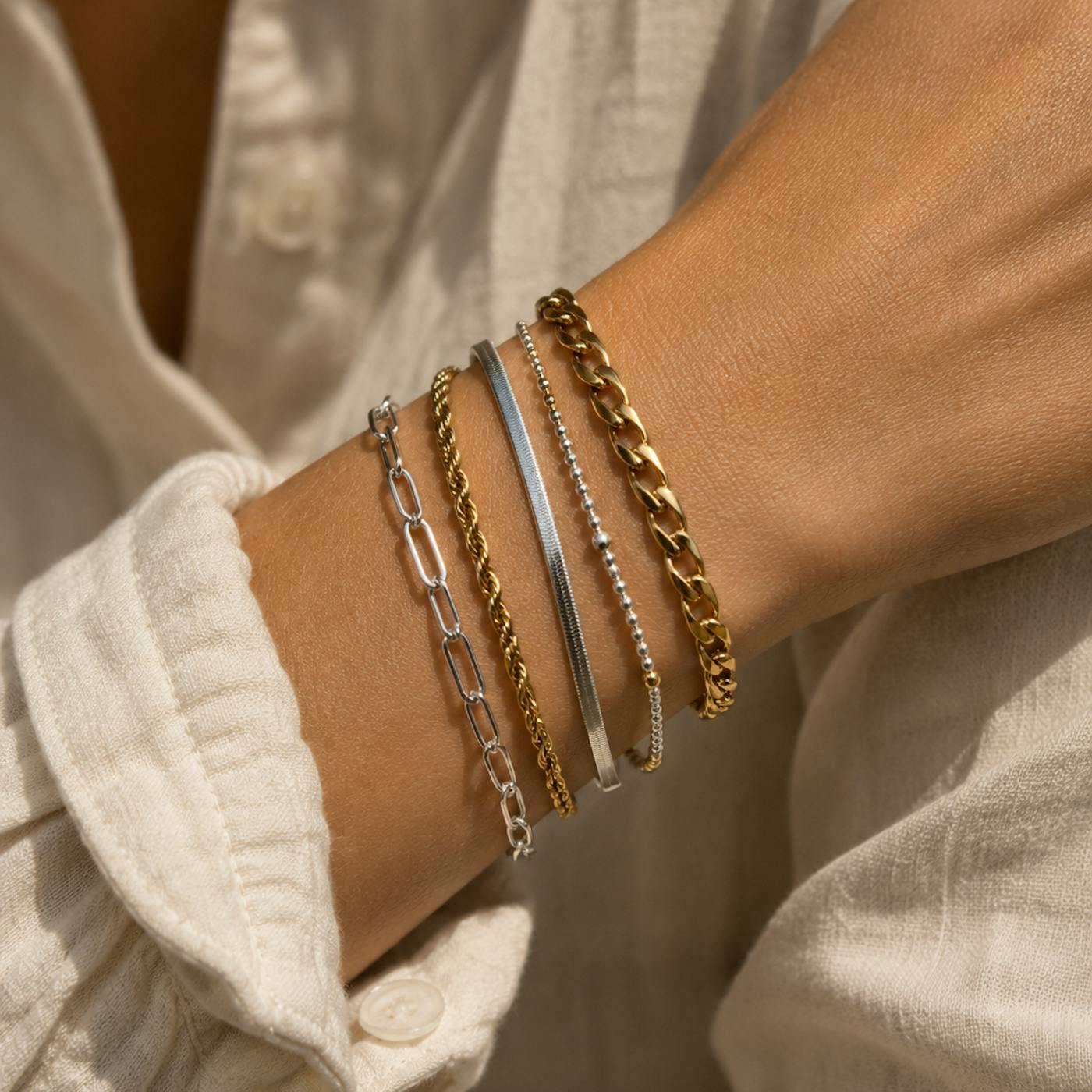 Can you mix gold and silver jewellery? Wrist with stacked gold and silver chain bracelets