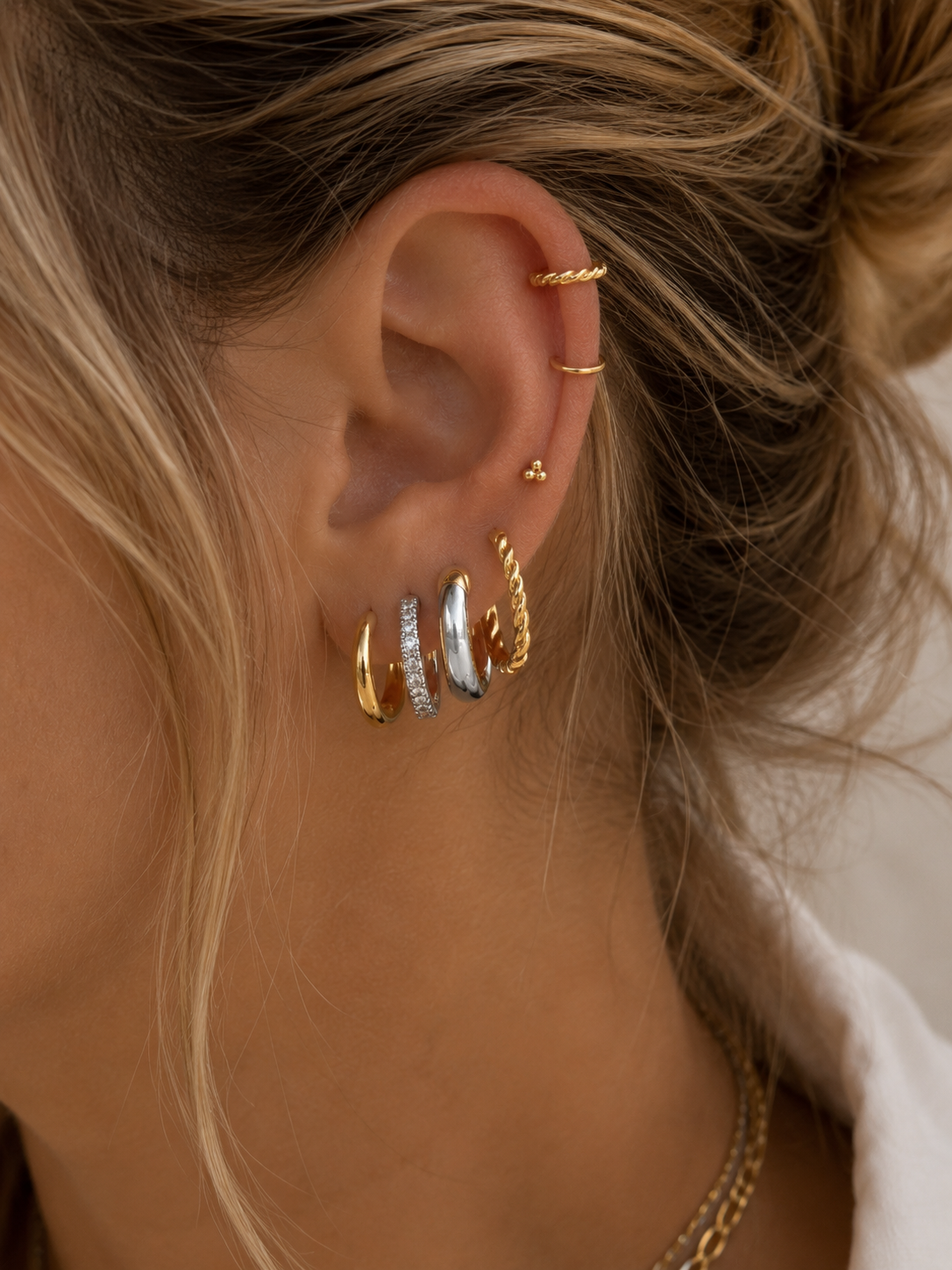 Ear stack with gold and silver hoop earrings and small studs