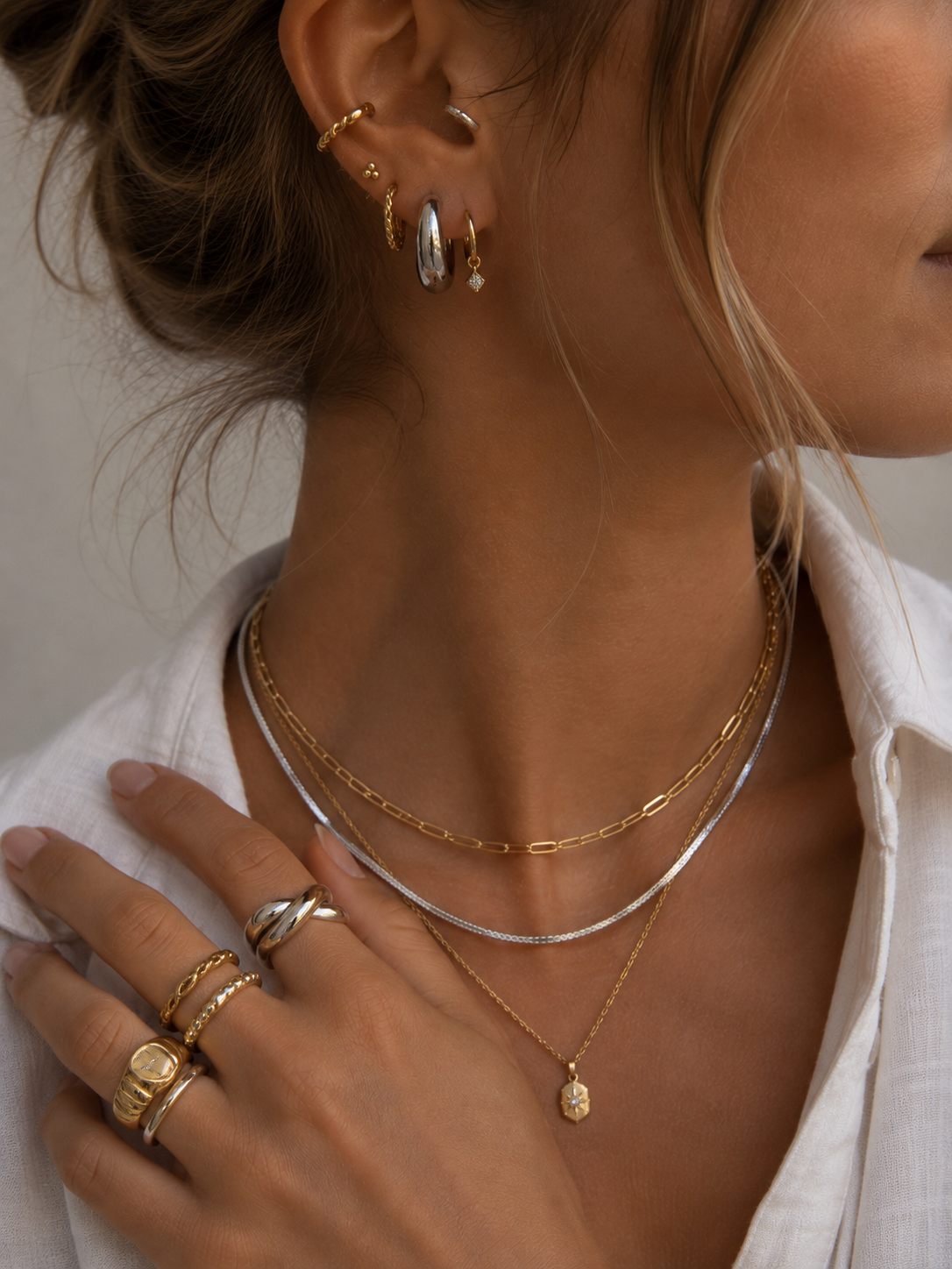 Mixed metal look with silver and gold necklaces, silver hoops and stacked rings