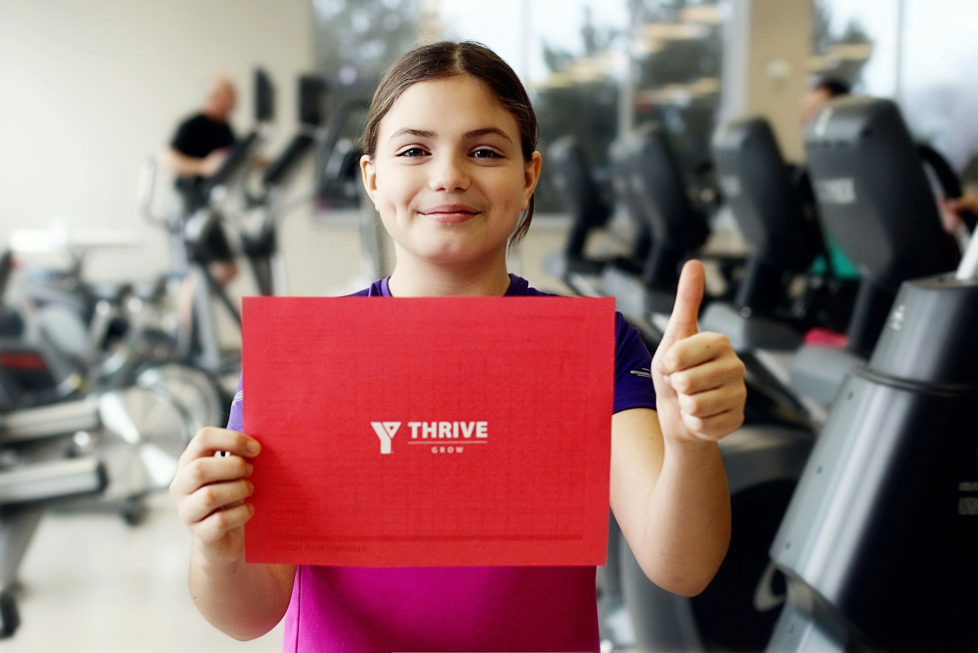 Smiling girl holding YThrive Sign