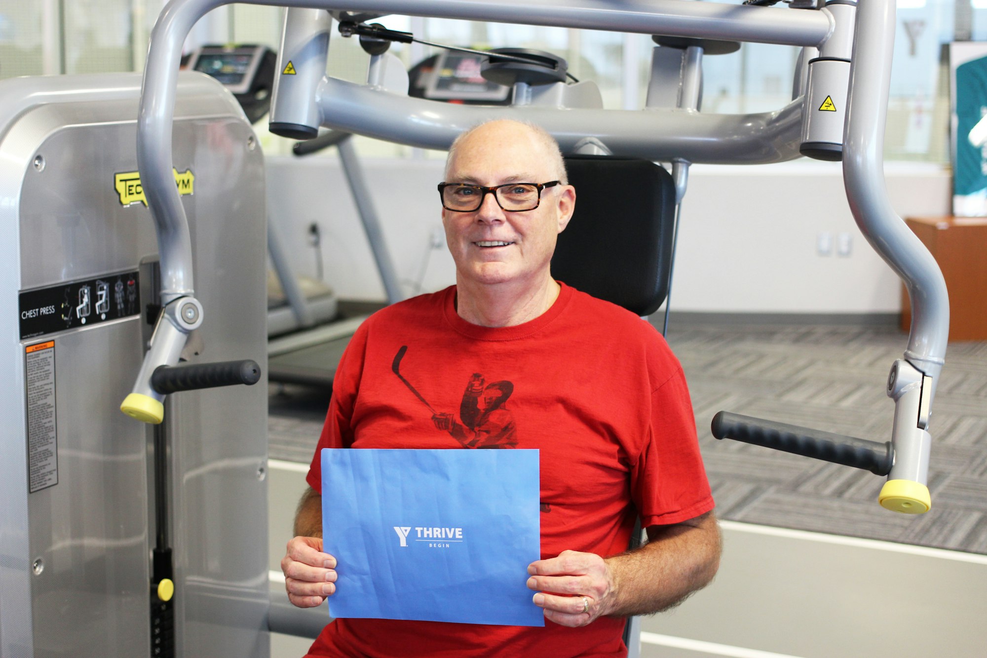 Smiling man holding YThrive sign