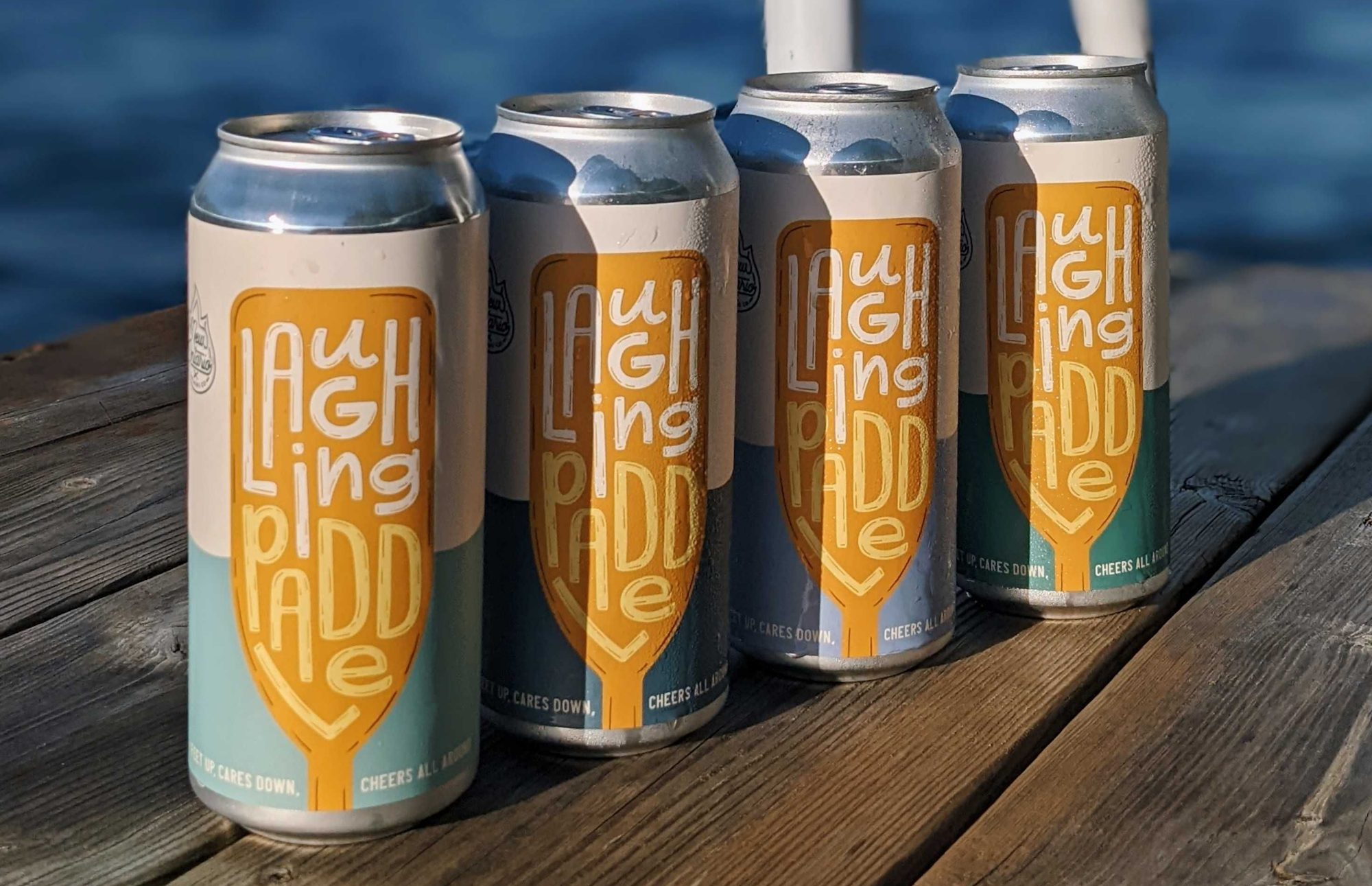 4 cans of Laughing Paddle beer lined up on a dock