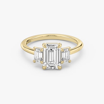 three stone emerald cut engagement ring with yellow band