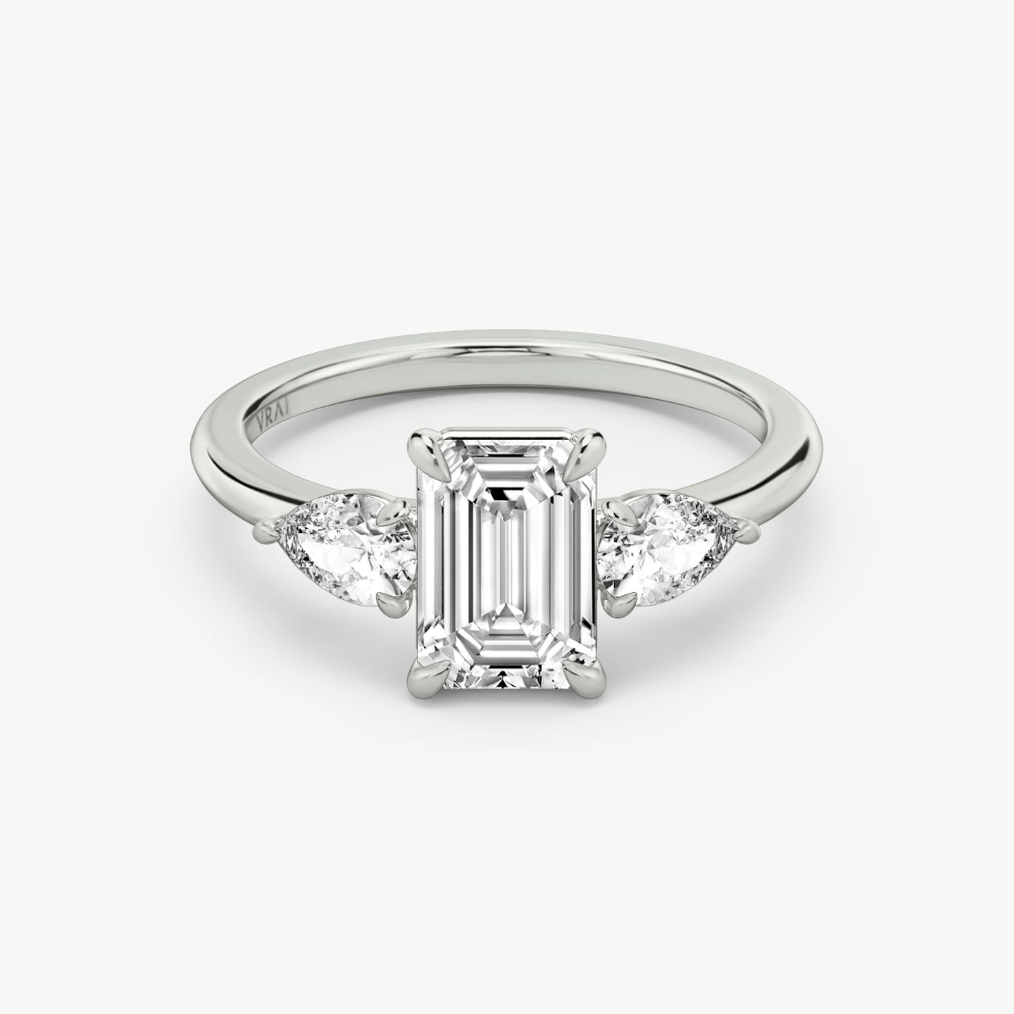 The Three Stone | emerald | 18k | white-gold | bandAccent: plain | sideStoneCarat: 0.25ct | sideStoneShape: pear | diamondOrientation: vertical | caratWeight: other