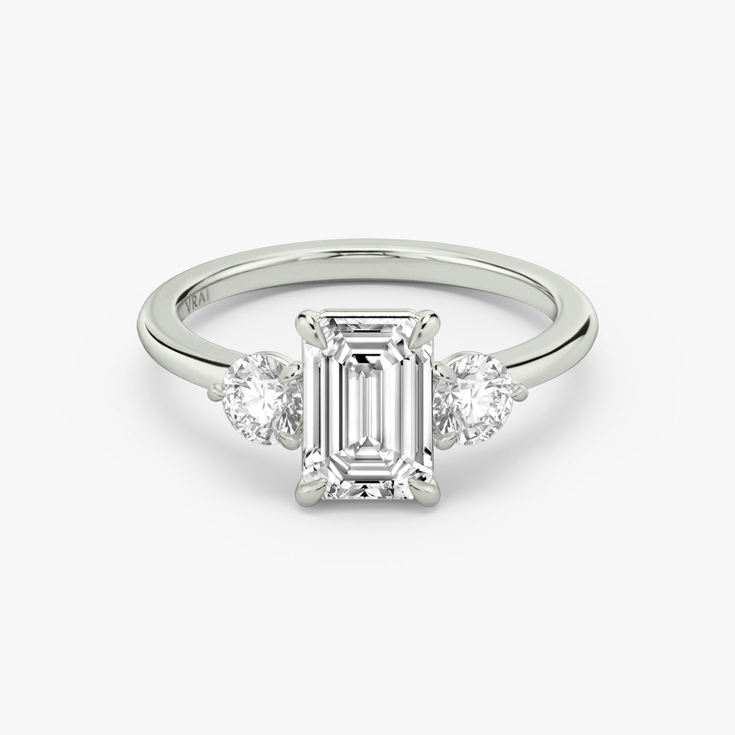 The Three Stone | emerald | 18k | white-gold | bandAccent: plain | sideStoneCarat: 0.25ct | sideStoneShape: round-brilliant | diamondOrientation: vertical | caratWeight: other