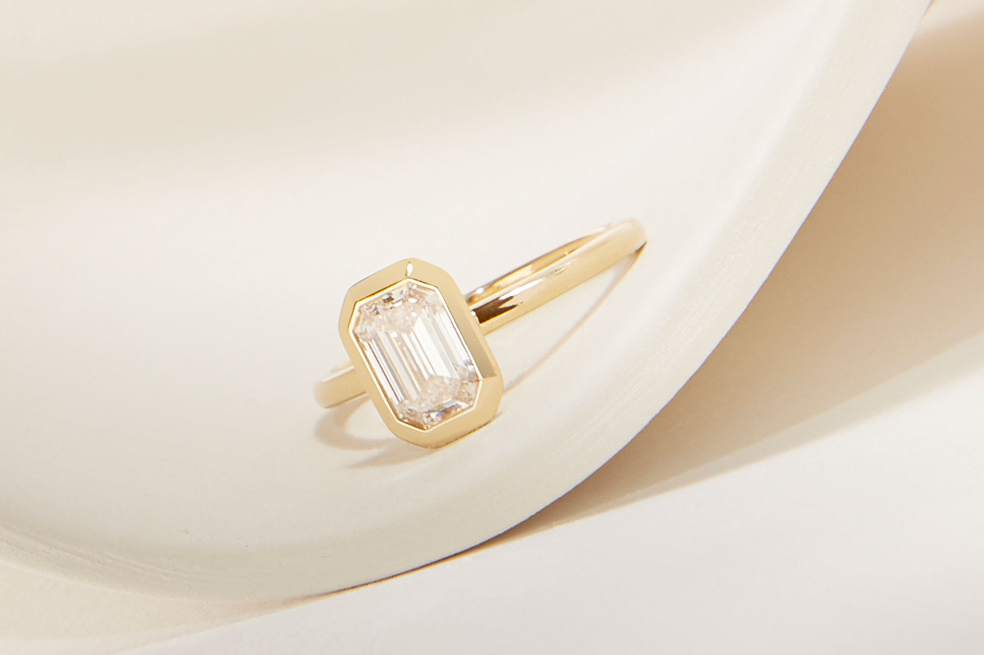 The emerald signature bezel engagement ring with yellow gold band