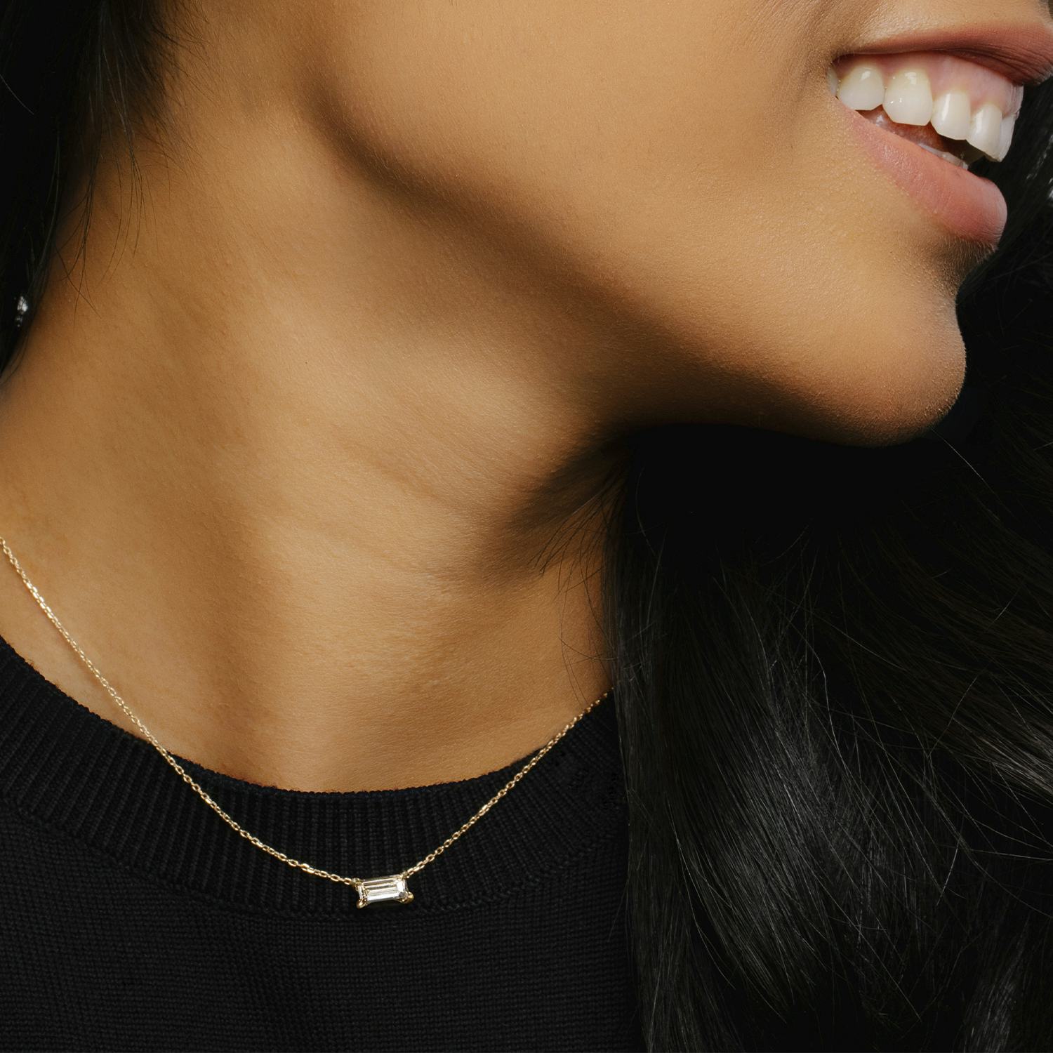 golden necklace with a baguette shaped diamond on a woman's neck