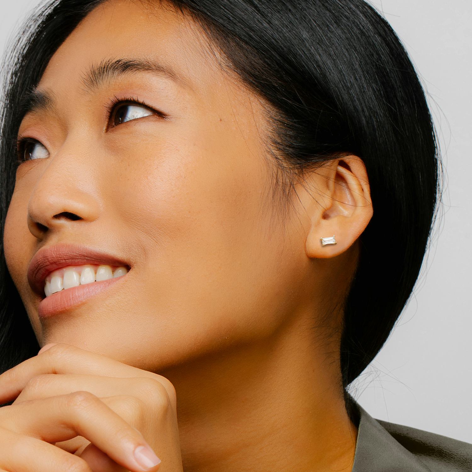 smiling woman shows a stud with a baguette shaped diamond on her left ear