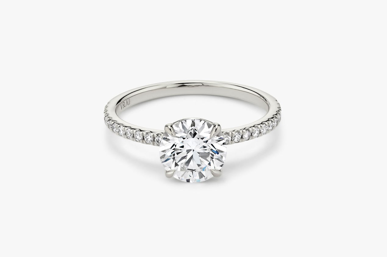 The Signature solitaire ring in 18k white gold with a round brilliant cut diamond and pavé band