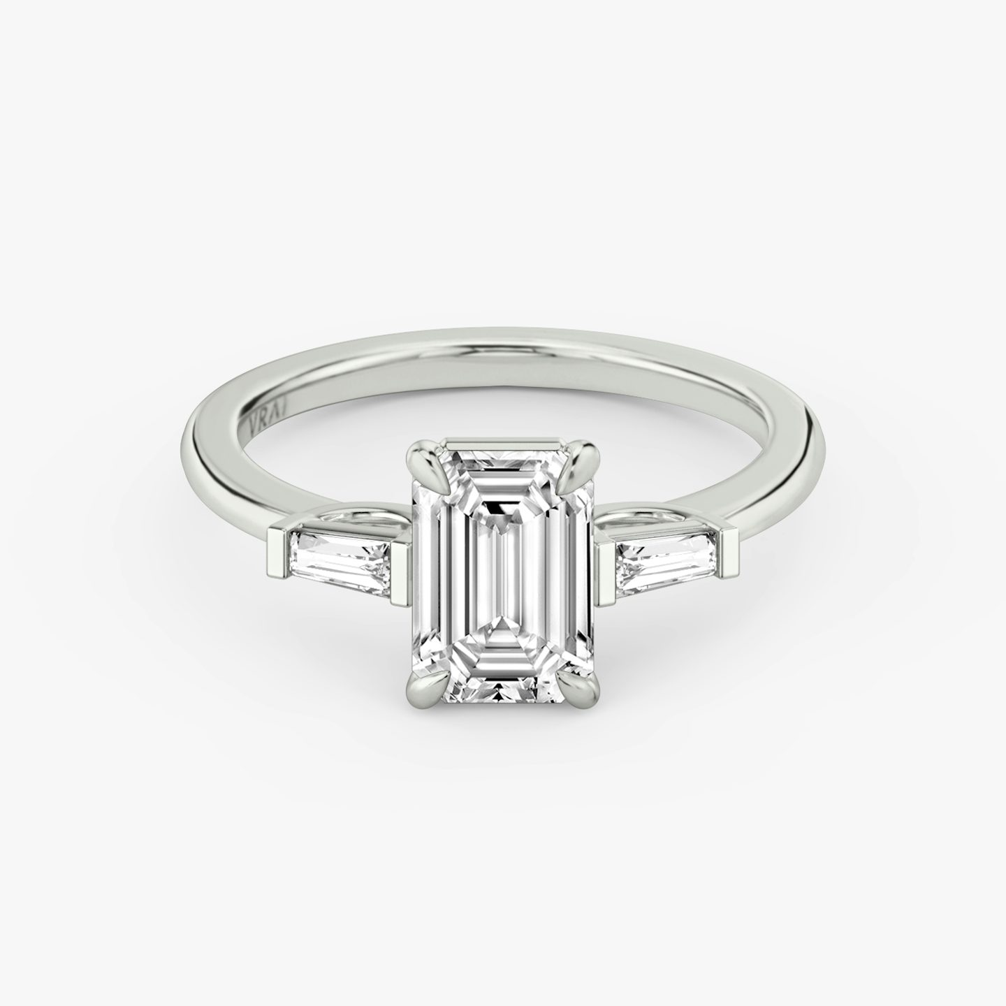 The Three Stone | emerald | platinum | bandAccent: plain | sideStoneCarat: 0.10ct | sideStoneShape: tapered-baguette | diamondOrientation: vertical | caratWeight: other
