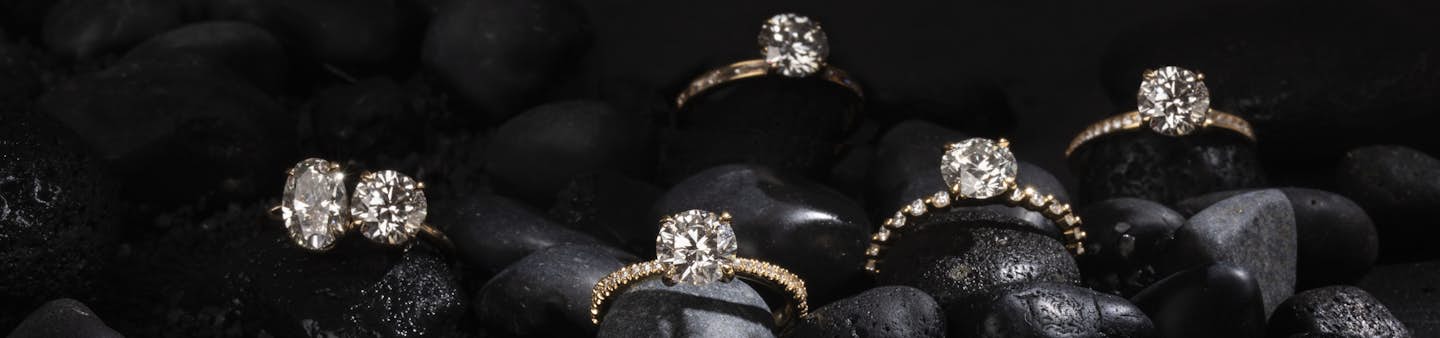 solitaire lab-grown diamond proposal rings on black rocks