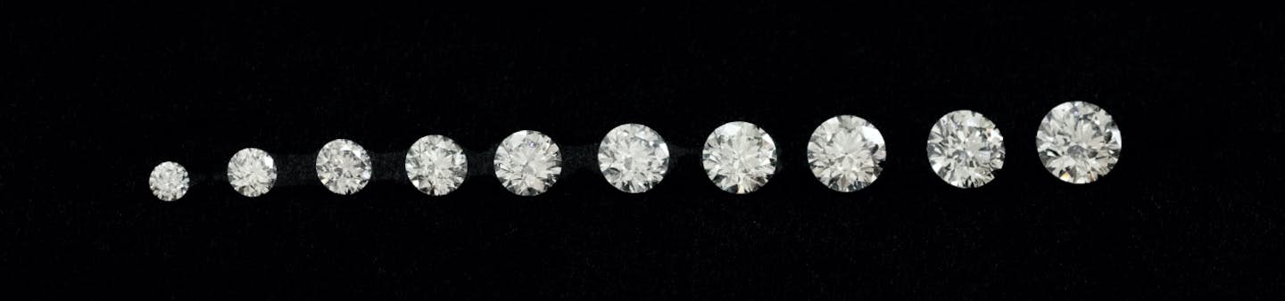 A row of Round Brilliant cut diamonds of various carat weights and sizes lined up in a row