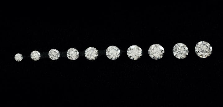 A row of Round Brilliant cut diamonds of various carat weights and sizes lined up in a row