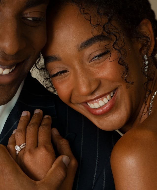 one couple cuddling with her hand visible showing engagement ring with oval diamond and wedding ring