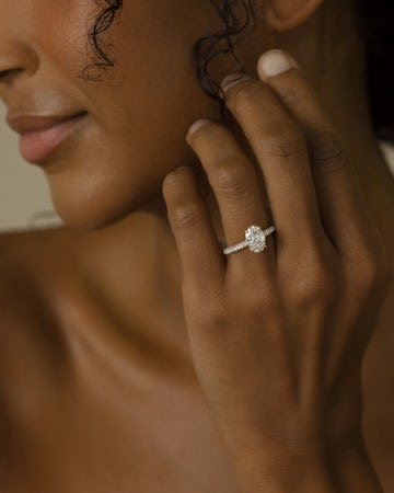 woman wearing an oval engagement ring with a pave band