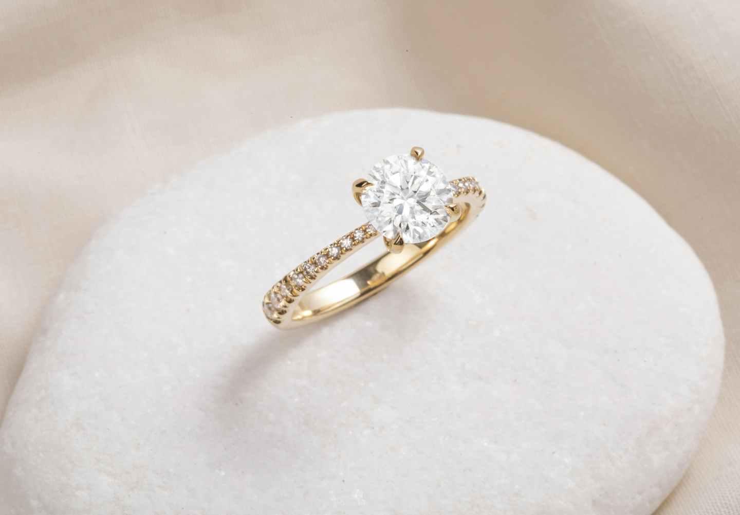 four prong engagement ring with a pave band and round diamond