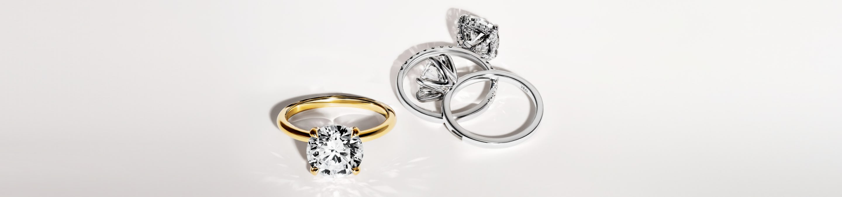 three engagement rings in classic solitaire styles in yellow gold, white gold and platinum