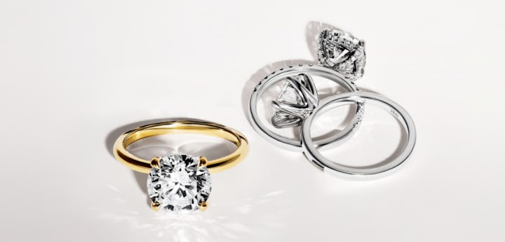 three engagement rings in classic solitaire styles in yellow gold, white gold and platinum