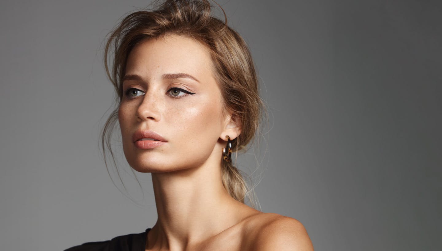 Woman looking to the side, wearing eyeliner with her hair pulled back