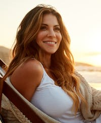 Woman sitting outside by the beach during the sunset