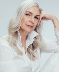 Older woman with white hair and a white button up shirt