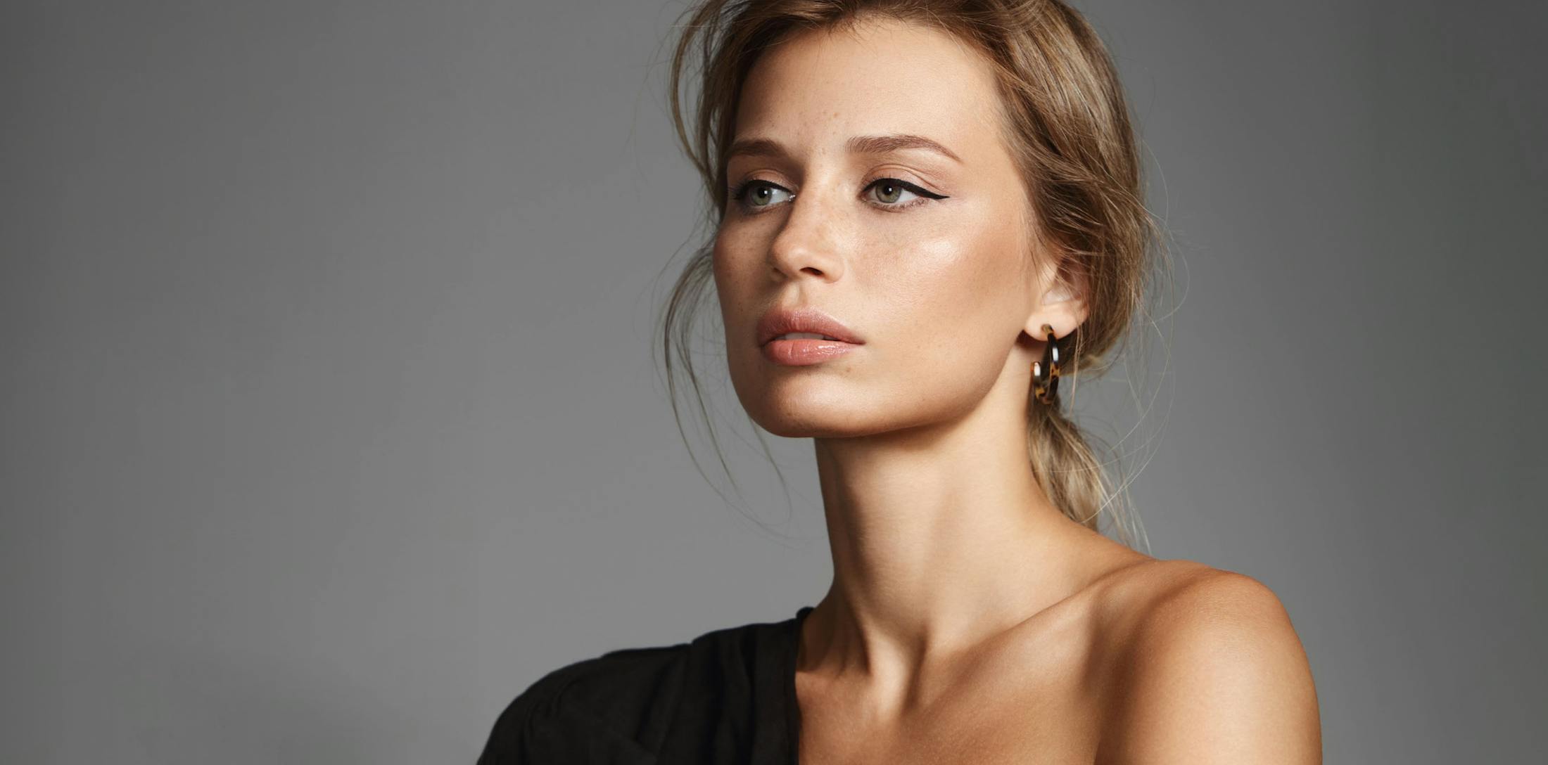 Woman with her hair pulled back looking forward wearing eyeliner