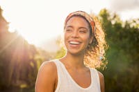 Woman smiling outside with the sun shining behind her