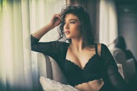 Woman in a black bra looking out the window