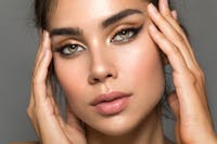 Woman with green eyes and full eyebrows looks at the camera