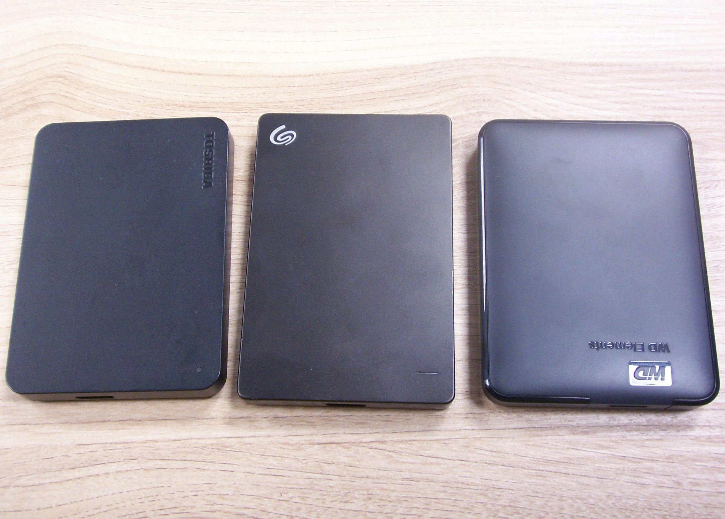 Trzy dyski twarde z interfejsem USB - Toshiba, Seagate, Western Digital, w czarnych obudowach.