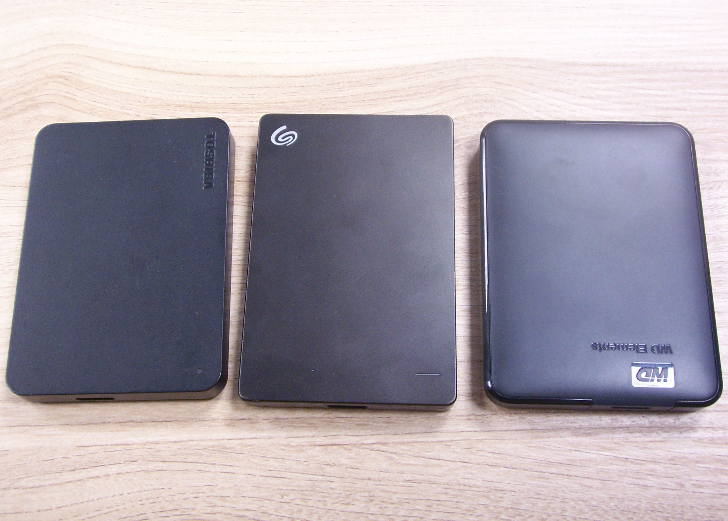Trzy dyski twarde z interfejsem USB - Toshiba, Seagate, Western Digital, w czarnych obudowach.