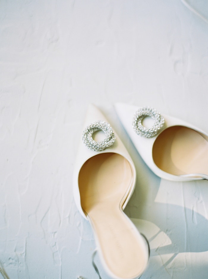 Whitney Heard photographs white bridal shoes in the sunlight.