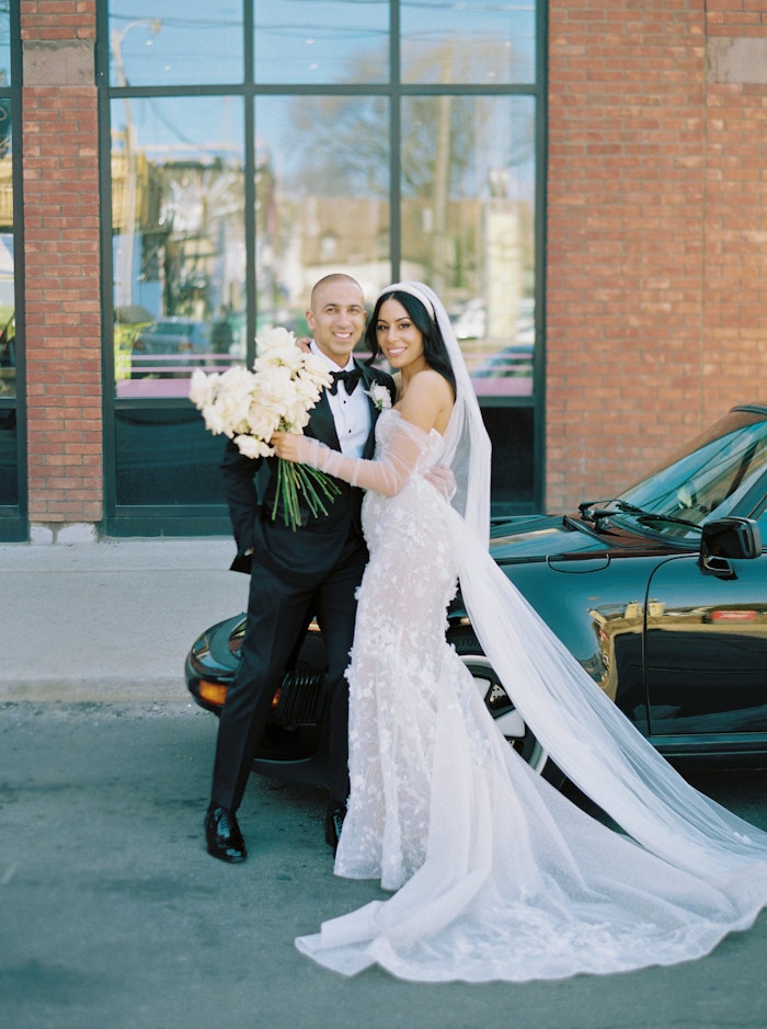 Happy Bride and Groom posing with a white bouquet and long veil outside the Broadview Hotel