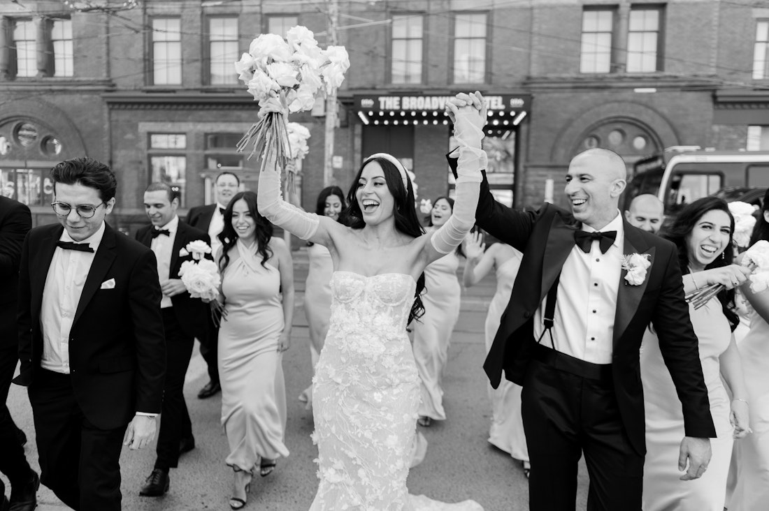 Laughter and black and white photography as a bridal party walks across the street infront of the Broadview Hotel.
