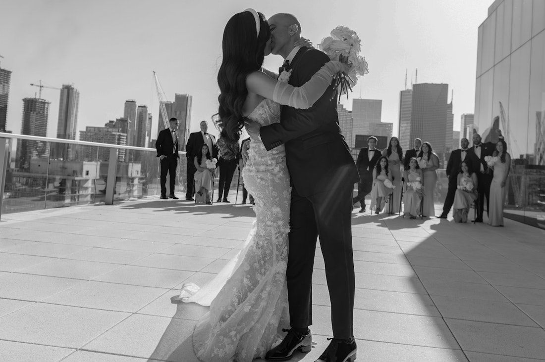 Romantic black and white photo of bride and groom kissing on the roof top of the globe and mail