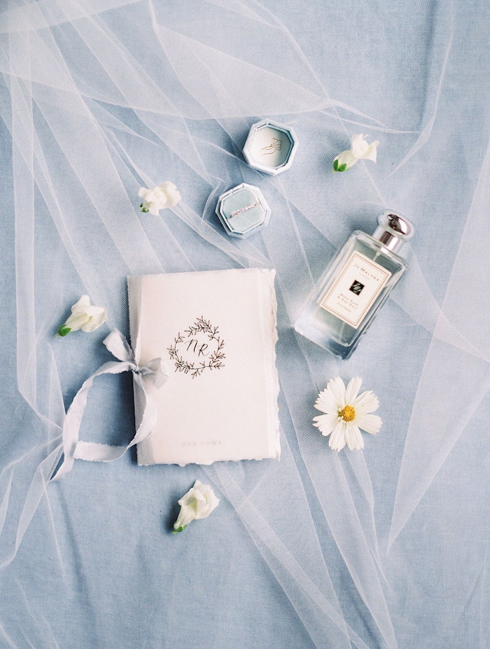 Toronto wedding photographer capturing soft blue wedding stationery flat lay with rings and perfume at Spadina House Museum