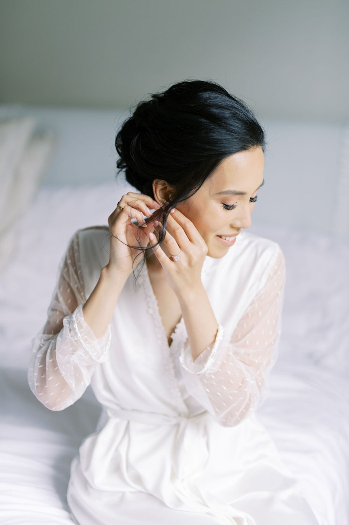 Bride putting on her earring in natural window light at Spadina House Museum Toronto wedding morning
