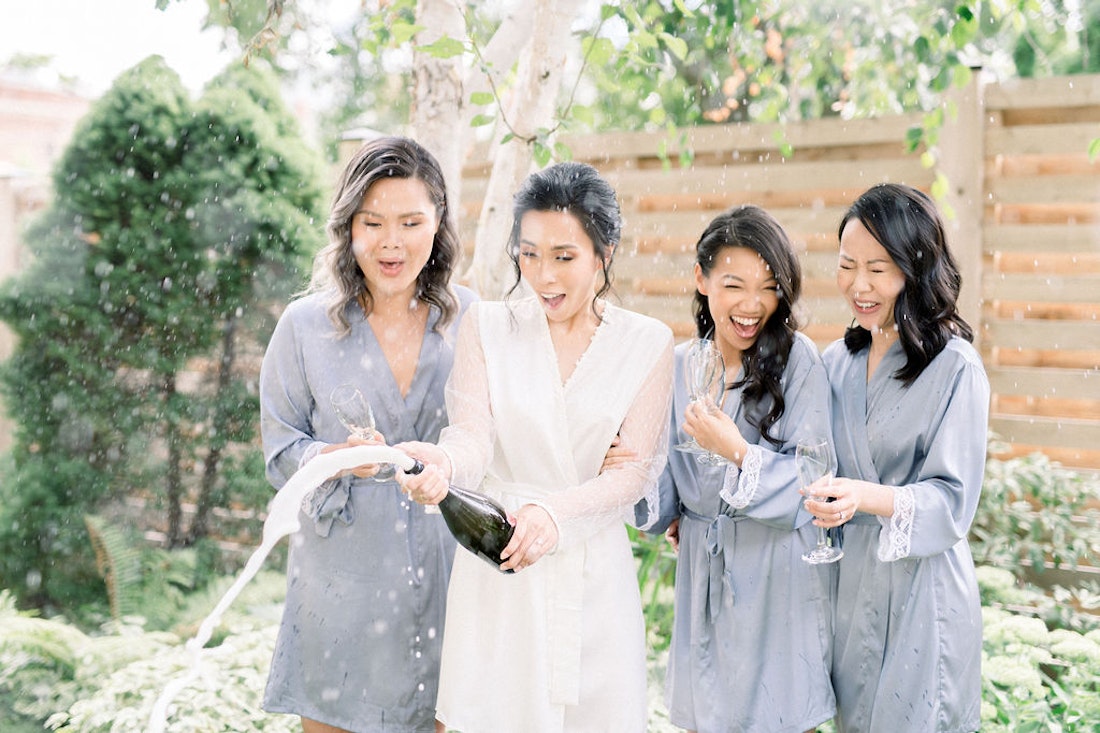Bridesmaids helping bride into wedding dress with soft blue colour palette at Spadina House Museum Toronto