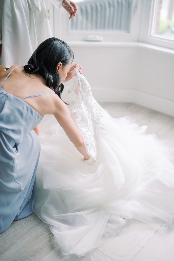Bridesmaids helping bride into wedding dress with soft blue colour palette at Spadina House Museum Toronto