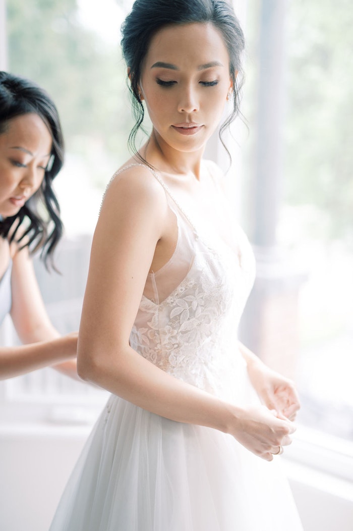 Bridesmaids helping bride into wedding dress with soft blue colour palette at Spadina House Museum Toronto