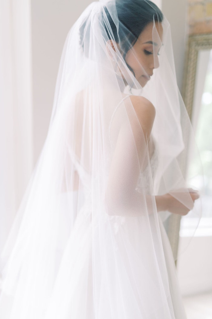 bride putting on her veil in wedding dress with soft blue colour palette at Spadina House Museum Toronto