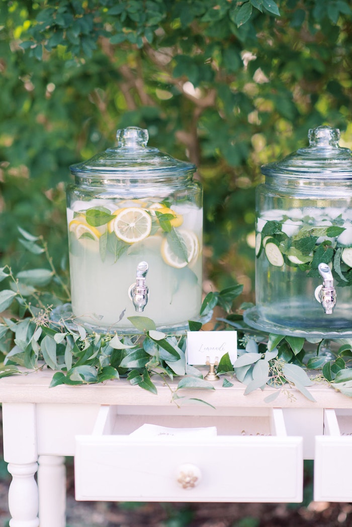 Water station for guests at Outdoor wedding ceremony at Spadina House Museum Toronto with guests seated in garden setting