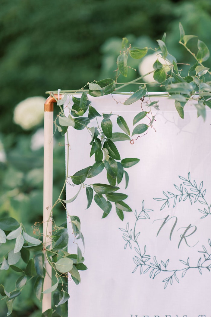 Welcome sign at Outdoor wedding ceremony at Spadina House Museum Toronto with guests seated in garden setting