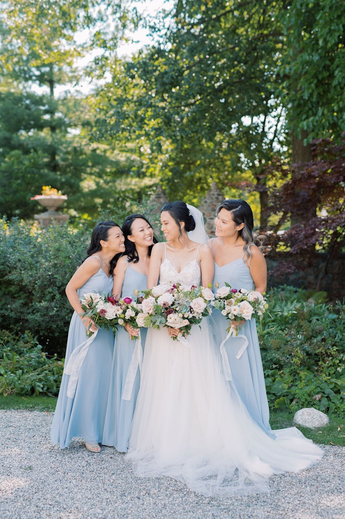 Bride and bridesmaids with bouquets in garden at Spadina House Toronto wedding