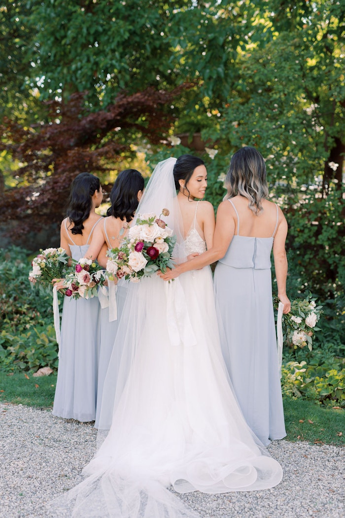 Bride and bridesmaids with bouquets in garden at Spadina House Toronto wedding